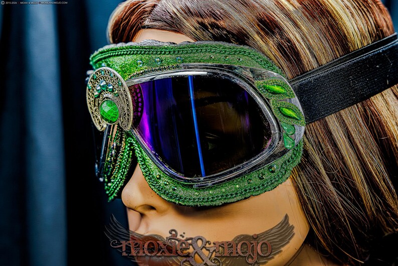 Pu&ograve; includere: Occhiali protettivi verdi con lenti scure riflettenti e una fascia elastica nera. La montatura &egrave; decorata con intricati ricami verdi, piccole perline verdi e un ornamento in filigrana metallica con una pietra verde liscia e ovale.