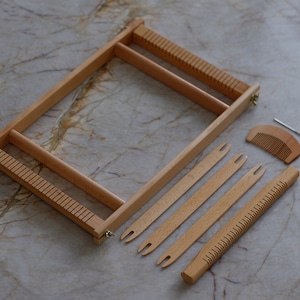 Peut inclure: Un ensemble de métier à tisser en bois, comprenant un cadre rectangulaire avec des côtés crantés, un peigne et plusieurs navettes. La couleur naturelle du bois et le design simple suggèrent un article d'artisanat ou de loisirs.