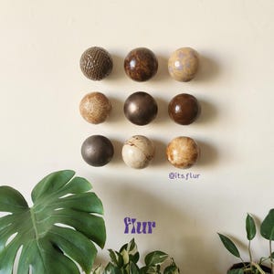 Könnte beinhalten: Neun runde Keramikknöpfe in verschiedenen Brauntönen, Beige und Weiß mit einer gesprenkelten Oberfläche. Die Knöpfe sind in drei Reihen zu je drei an einer weißen Wand angeordnet. Der Text "@its.flur" und "flur" ist in der rechten unteren Ecke des Bildes sichtbar.
