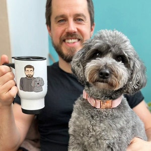 Peut inclure: Un mug de voyage blanc avec une poignée et un couvercle noirs, avec une illustration de dessin animé d'un homme et d'un chien. Le chien est un caniche gris portant un collier rose. L'homme tient le mug.