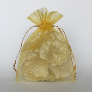 May include: A gold sheer organza bag filled with gold rose petals. The bag has a drawstring closure.