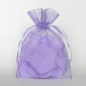 May include: A sheer lavender organza drawstring bag filled with matching lavender fabric flower petals. The bag is tied at the top with a matching ribbon. The petals are visible through the translucent fabric.