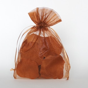 May include: A brown sheer organza bag filled with brown silk rose petals. The bag has a gold drawstring.