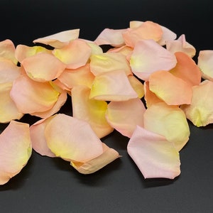 May include: A pile of light pink and yellow rose petals. The petals are soft and delicate, and they would be perfect for a wedding or other special occasion.