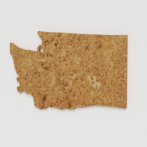 May include: A cork cutout in the shape of the state of Washington. The cutout is a light brown color with a textured surface. The state outline is visible against a white background. The product is a decorative item.