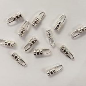 May include: Silver-toned metal jewellery findings with a loop on one end and a series of beads on the other end. The findings are approximately 2.5 cm long.