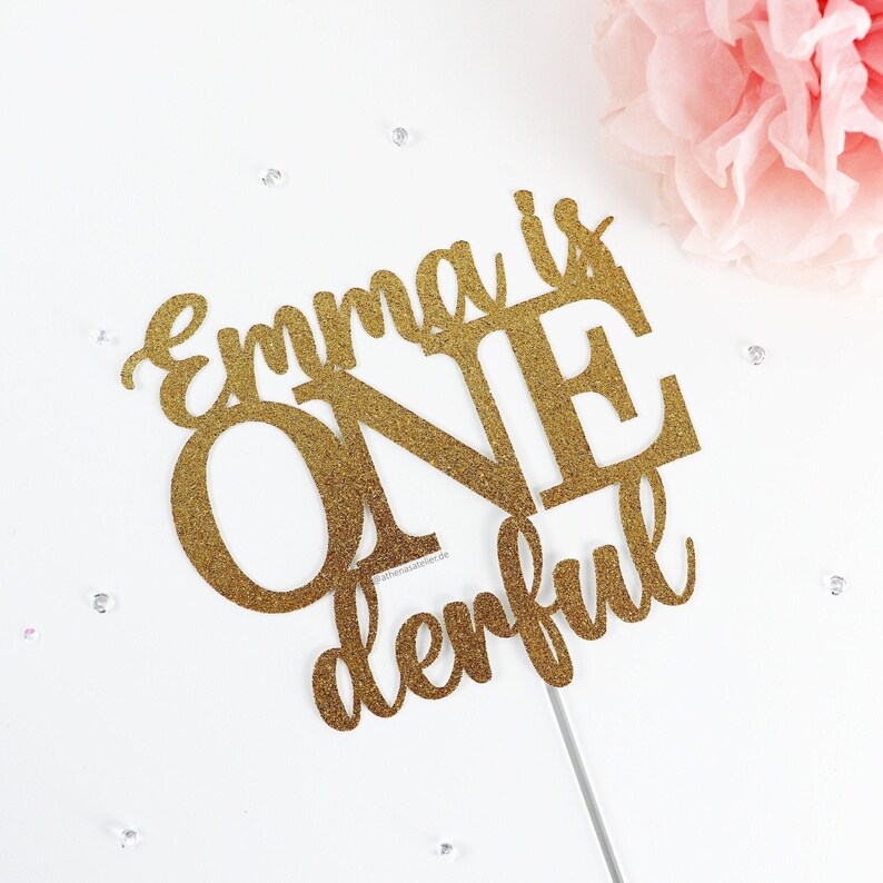 May include: Gold glitter cake topper with the text "Emma is one derful".