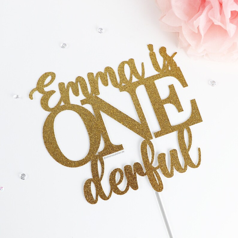 May include: Gold glitter cake topper with the text "Emma is one derful".