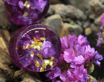 May include: Two round purple resin earrings with embedded dried flowers and gold flakes.