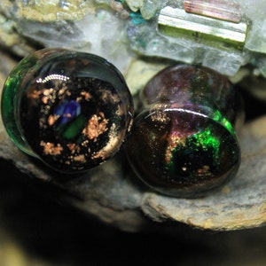 Peut inclure: Paire de jauges d'oreille en verre avec un motif en spirale noir, vert et cuivre. Les jauges ont une finition brillante et irisée.