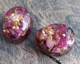 May include: Two round resin cabochons with pink and gold flecks. The cabochons are translucent and have a glossy finish.