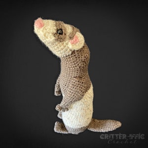 crocheted ferret looking up and to the left on a black background