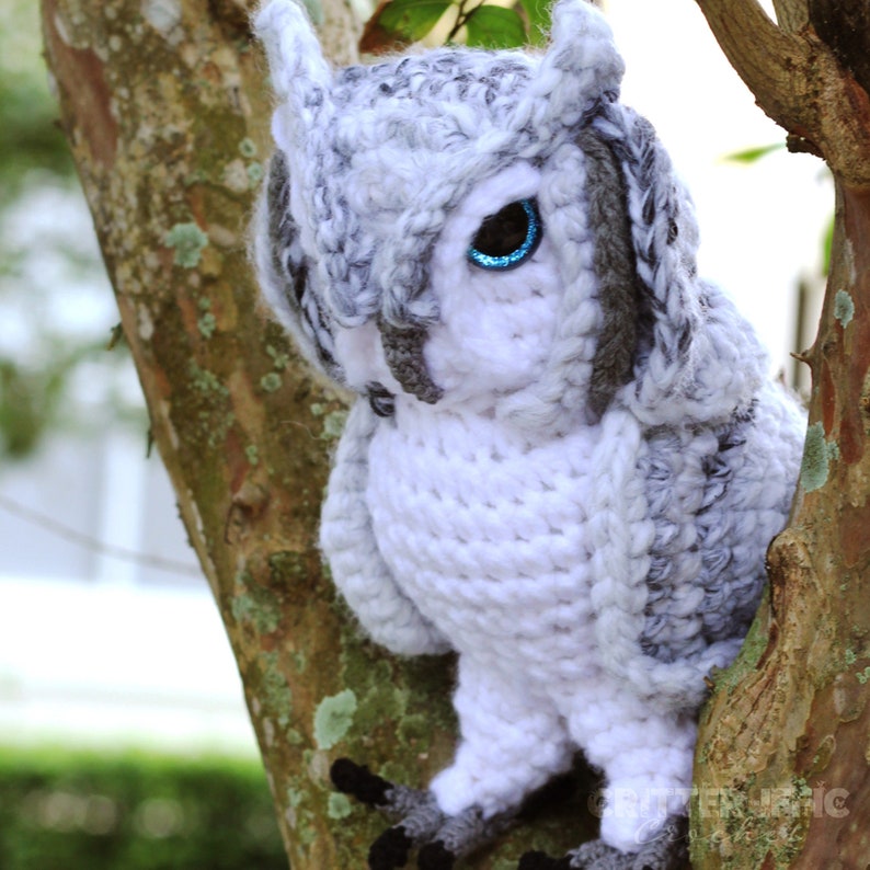 realistic crocheted owl sitting in in a tree