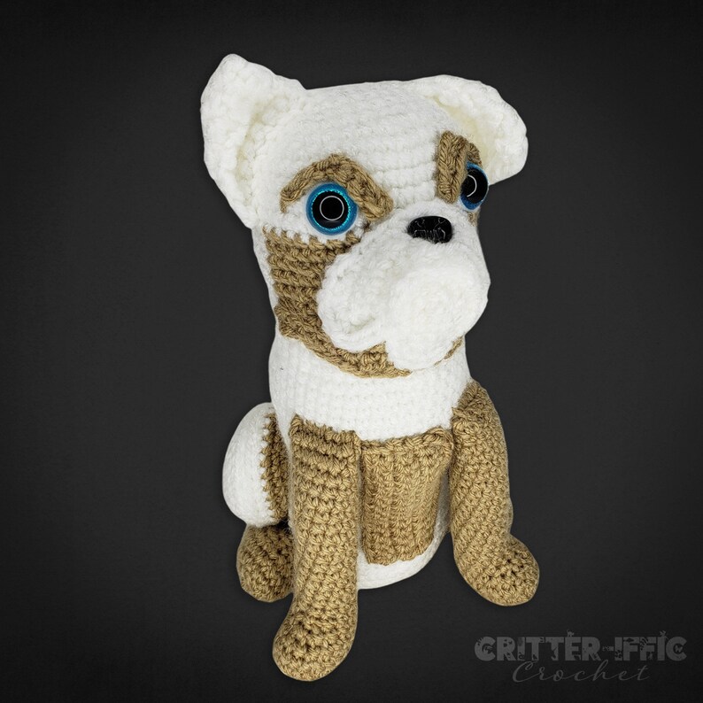 Crocheted brussels griffon dog with blue eyes looking right on a black background