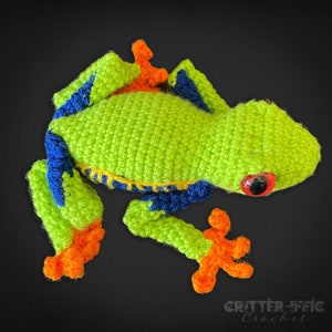 crocheted red eyed tree frog looking left on a black background
