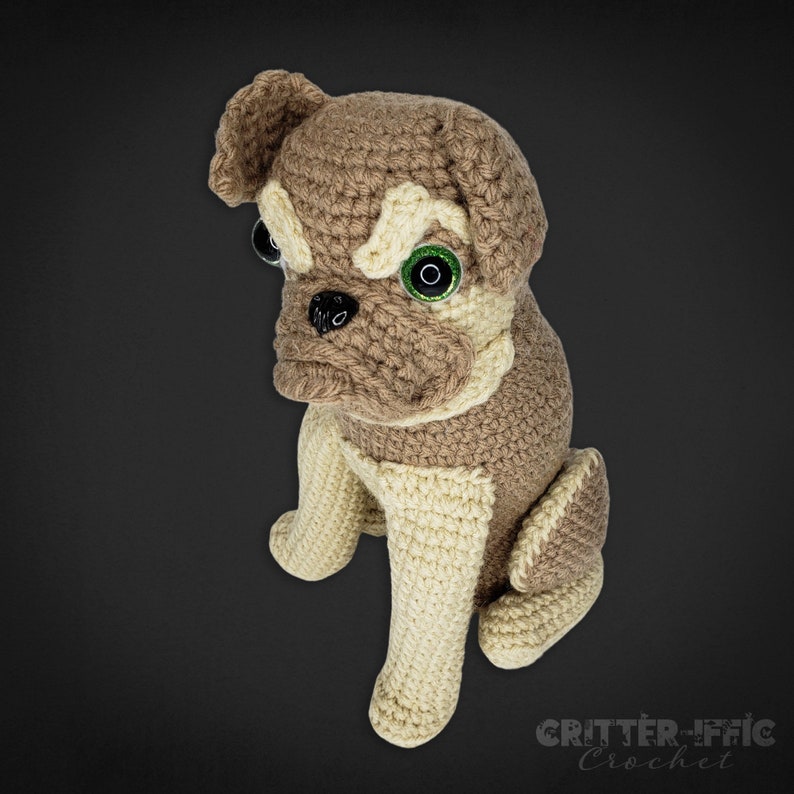 Crocheted brussels griffon dog looking left on a black background