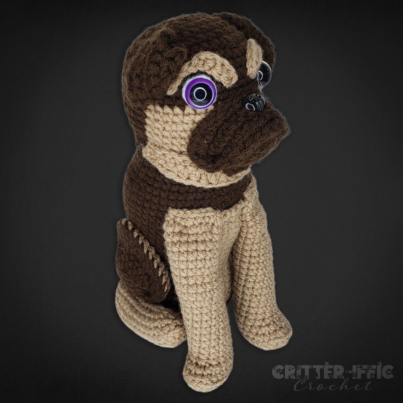 Crocheted brussels griffon dog with purple eyes on a black background