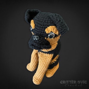Crocheted brussels griffon dog looking left on a black background