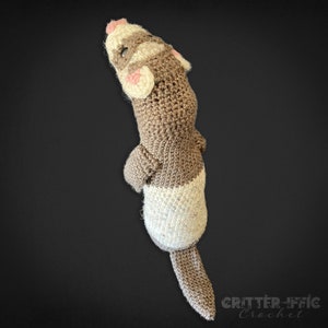 back view of a crocheted ferret on a black background