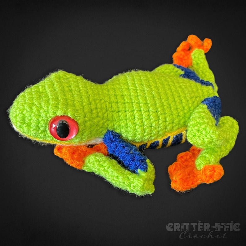 crocheted red eyed tree frog facing left on a black background