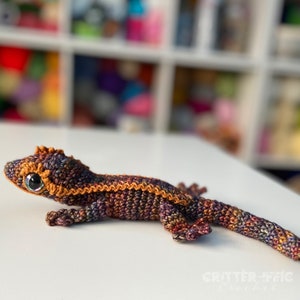 curious crocheted crested gecko sitting on a table. brown and gold shades with big bright eyes