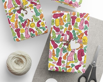 May include: A white background with three rolls of wrapping paper featuring a colourful pattern of various shapes. The wrapping paper is tied with twine and has a white tag attached.