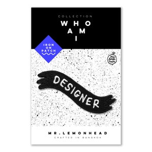 May include: Black and white iron-on patch with the word "DESIGNER" in a banner shape. The patch is part of the "WHO AM I" collection by MR. LEMONHEAD, crafted in Bangkok.