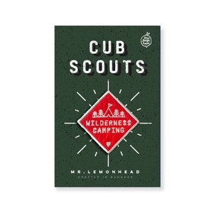 Op de afbeelding: Een rode ruitvormige patch met witte tekst die "WILDERNESS CAMPING" luidt en een klein rood hartje in de onderste hoek. De patch is omgeven door een witte stervormige uitbarsting op een donkergroene achtergrond. De tekst "CUB SCOUTS" staat bovenaan de afbeelding en "MR. LEMONHEAD CRAFTED IN BANGKOK" staat onderaan.