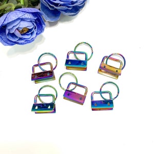 May include: Six iridescent rainbow key rings with a square metal loop and a small key ring. The key rings are on a white background.