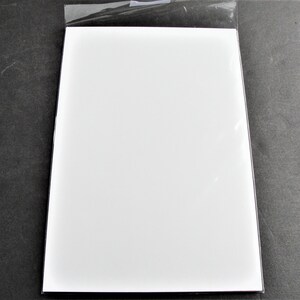 May include: A white sheet of paper in a clear plastic sleeve.