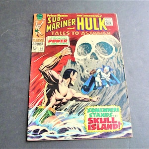 May include: A comic book cover featuring the Sub-Mariner and the Incredible Hulk. The cover is red, yellow, and blue with a skull image in the background. The text on the cover reads "Prince Namor, The Incredible Hulk, Sub-Mariner, Tales to Astonish, Featuring the Pounding Power of Prince Namor, Somewhere Stands... Skull Island!"