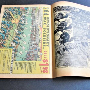 May include: A vintage comic book advertises a set of 204 Revolutionary War Soldiers for $1.98. The ad features a detailed illustration of soldiers in battle, with a red, white, and blue American flag in the background. The ad also includes a coupon for the product.