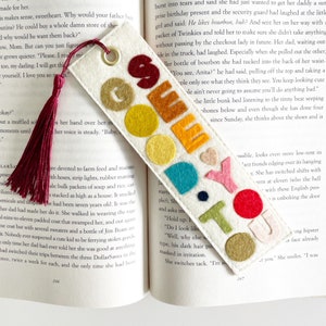 May include: A white felt bookmark with the words "Go Say Hi To You" in colorful felt letters. The bookmark has a red tassel.