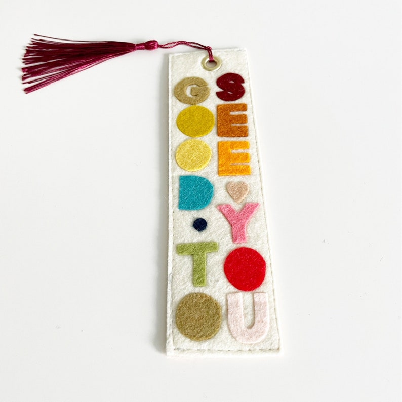 May include: A white felt bookmark with a red tassel. The bookmark has the words "See You" in colorful felt letters.