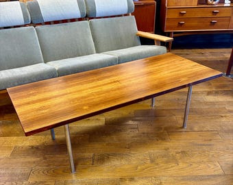 May include: A rectangular wooden coffee table with a light brown wood top and silver metal legs. The table is sitting on a hardwood floor.