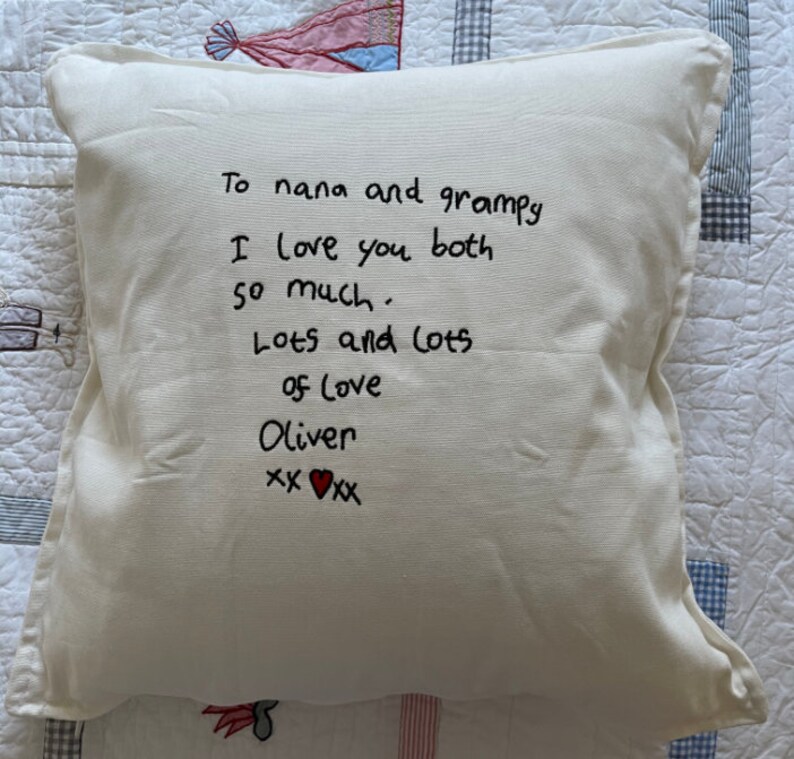Peut inclure: Oreiller blanc avec un texte manuscrit noir qui dit "To nana and grampy I love you both so much. Lots and lots of love Oliver xx &hearts; xx"