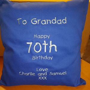 Peut inclure: Un coussin bleu avec une broderie blanche qui dit "To Grandad Happy 70th Birthday Love Charlie and Samuel XXX"