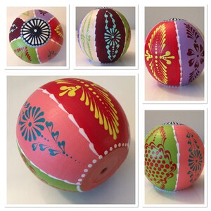 May include: Four hand-painted ornaments with different designs. Each ornament features a variety of colors, including pink, red, green, yellow, blue, purple, and white. The ornaments are decorated with intricate patterns and designs.