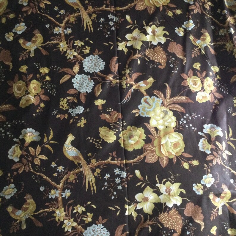 May include: A dark brown fabric with a repeating pattern of stylized birds, flowers, and leaves. The flowers are in shades of yellow and white, and the leaves are in shades of brown and green.