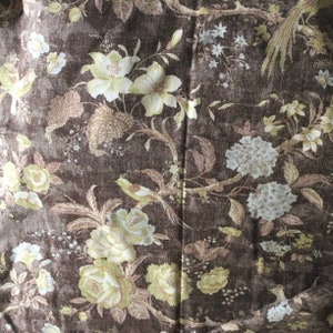 May include: A brown fabric with a floral pattern. The flowers are in shades of beige, white, and brown. The fabric has a subtle texture.