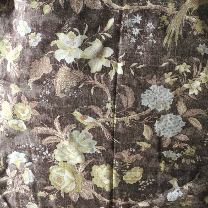 May include: A brown fabric with a floral pattern. The flowers are in shades of beige, white, and brown. The fabric has a subtle texture.