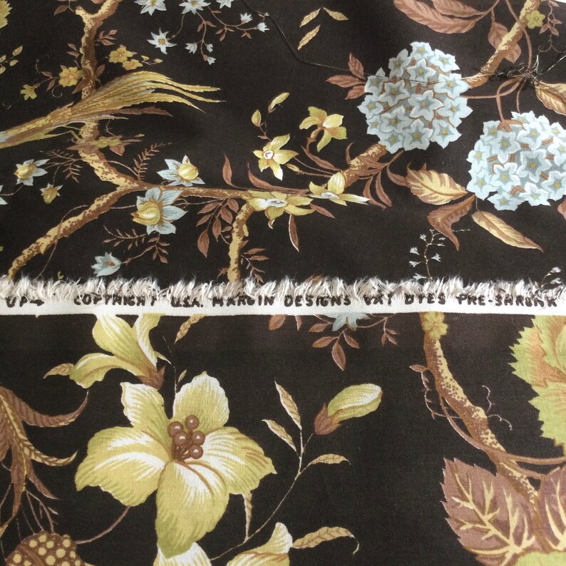 May include: Brown fabric with a floral pattern featuring yellow, white, and brown flowers. The fabric has a white label with the text "Copyright USA, Hardin Designs Vat Dyes Pre-Shrunk".