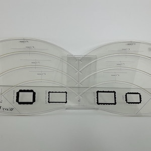 May include: A transparent acrylic quilting template with curved edges and rectangular cutouts. The template has printed markings and the text "Scallop Edge" and "Mary Edge".