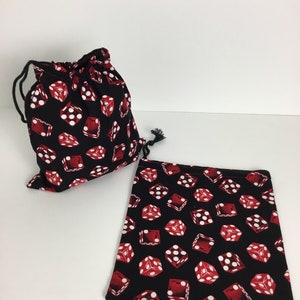May include: Two dice bags, one drawstring and one open, are displayed. Both are black with a repeating pattern of red dice with white pips. The drawstring bag is closed with a black cord. The open bag is rectangular.