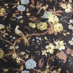 May include: A black fabric with a floral pattern featuring yellow, brown, and blue flowers and birds. The fabric has a repeating pattern.