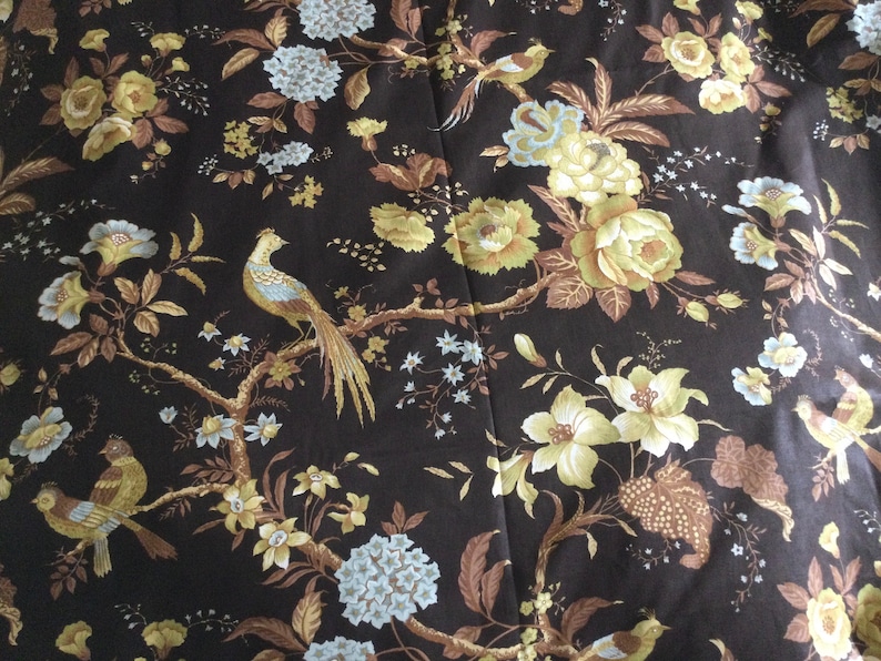 May include: A black fabric with a floral pattern featuring yellow, brown, and blue flowers and birds. The fabric has a repeating pattern.