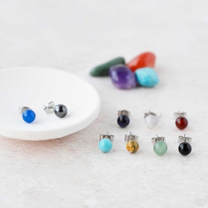 May include: A set of 10 gemstone earrings with silver posts. The earrings feature a variety of colours, including blue, green, red, black, and brown.