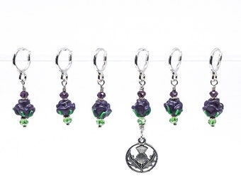 May include: Set of six purple thistle flower stitch markers with green accents and silver rings. The markers are attached to a silver charm with a thistle design.