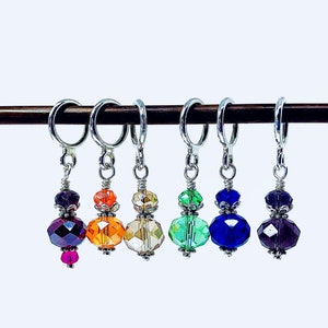 Peut inclure: Six marqueurs de point en cristal coloré avec des anneaux argentés et des accents de fil argenté. Les marqueurs sont suspendus à une baguette en bois.