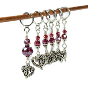 May include: Set of six silver stitch markers with red crystal beads and ornate heart charms.